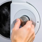 Detailaufnahme einer Hand, die mit einem Entlüftungsschlüssel ein Heizkörperventil öffnet, während Luft und dann Wasser austreten.