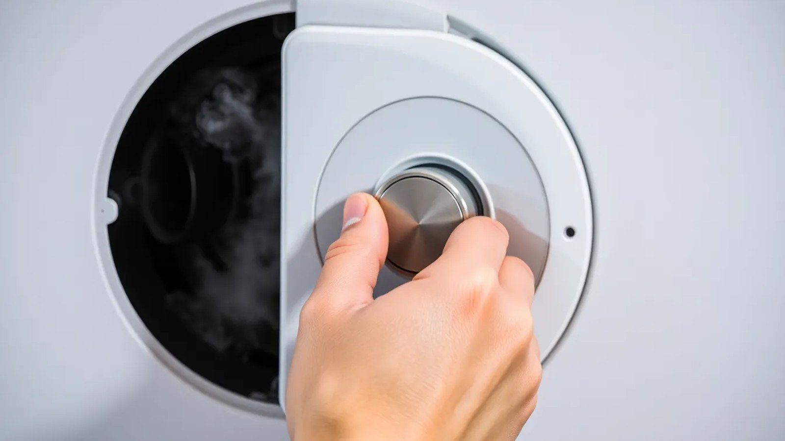 Detailaufnahme einer Hand, die mit einem Entlüftungsschlüssel ein Heizkörperventil öffnet, während Luft und dann Wasser austreten.