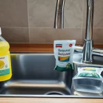 Spülmittel und Backpulver zur Abflussreinigung neben einer Küchenspüle