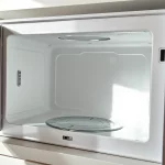 Detailaufnahme einer Mikrowelle mit beschädigtem Innenraum und defekter Mica-Platte als Ursache für Blitze.